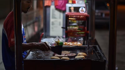 An employee cooks burgers and hot dogs at a roadside stall in Karak, outside Kuala Lumpur AFP PHOTO / MOHD RASFAN