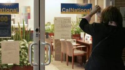 FDIC spokesperson Roberta Valdez shows identification to gain entry at a California National Bank branch in downtown Los Angeles.