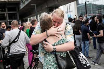 People hug each other in front of the Field's shopping mall in Copenhagen, where a gunman killed three people. AFP