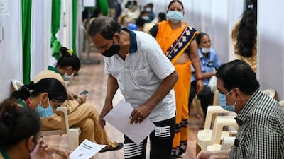 People fill out personal information forms before getting inoculated against Covid-19 at a vaccination centre in Mumbai. AFP