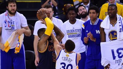Players on the bench of the Golden State Warriors watch as Stephen Curry defends against LeBron James of the Cleveland Cavaliers during Game 5 of the 2015 NBA Finals on June 14, 2015 at the Oracle Arena in Oakland, California. The Warriors defeated the Cavaliers 104-91 to lead the best of seven series 3-2. AFP PHOTO / FREDERIC J. BROWN