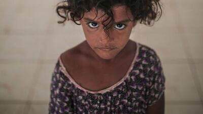 Aseya, 3, poses for a photo in her family's room in at an orphanage where she is staying.