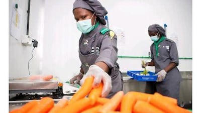 Chef Phelistas Vunya, left, and kitchen hand Farouk Mutebi get to work at Food Pro Solutions' industrial kitchen in Jebel Ali, Dubai. Callaghan Walsh / The National