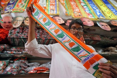 A man folds a stole with the logo of India's main opposition Congress party inside a shop selling various political parties' merchandise. Reuters