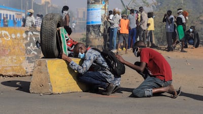 Sudanese protesters take cover during clashes with security forces at an anti-coup protest, in Khartoum, Sudan, 09 January 2022. Security forces fired tear gas to disperse protesters gathering in Khartoum and attempting to march towards the presidential palace, as part of the continuing protesting movement against a military coup in October 2021. The protest was organized a day after the UN envoy for Sudan said the international group will invite different parties for talks in Sudan to end the crisis. EPA