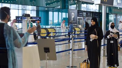 Saudi passengers queue for a temperature check at Terminal 5 in the King Fahad International Airport, designated for domestic flights, in Riyadh after authorities lifted the ban on domestic flights. AFP