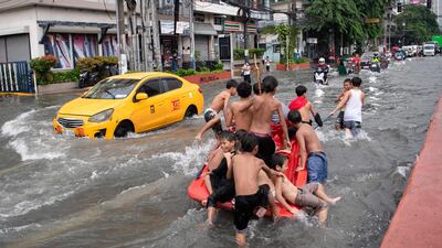 Children play on a waterlogged street in Manila after Typhoon Wipha brought heavy rain and flooding to the Philippines. AFP