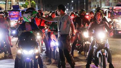 A traffic officer checks temperatures of motorcycle riders at a checkpoint as part of the precautionary measures against the spread of the new coronavirus in Manila. AP