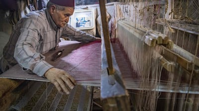 Ouazzani works on a tapestry at his workshop. AFP