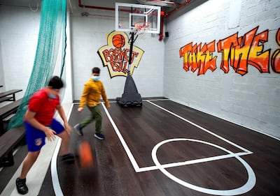 Visitors shoot hoops at the indoor basketball court at Sneaker District. Victor Besa / The National