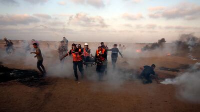 Medics evacuate a wounded youth while others run to cover from teargas fired by Israeli troops near the Gaza Strip border with Israel. AP
