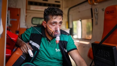 A member of the Alhayat Volunteer Team uses an oxygen mask while receiving treatment for smoke inhalation as a wildfire ravages the countryside near the town of Rabia in Syria. AP