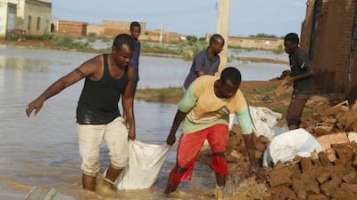 Residents wade through flood water in El Manaqil, Sudan. Getty
