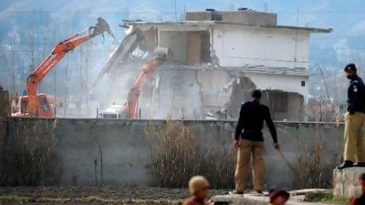 Pakistani police stand guard as security personnel conduct demolition works on the compound where Osama bin Laden was killed last year in the northwestern town of Abbottabad.