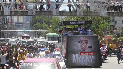 Pacquiao waves to the crowds during a motorcade in Manila May 13, 2015 after arriving back from Las Vegas. Romeo Ranoco / Reuters