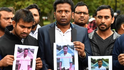 Friends of a missing man Zakaria Bhuiyan hold up photos of him outside a refuge centre in Christchurch. AAP Image via AP