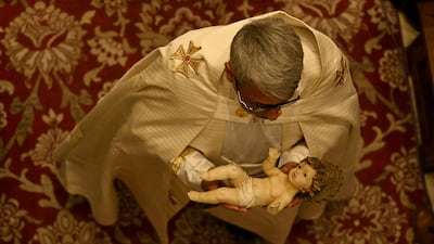 A Catholic priest walks down the aisle during a Christmas Eve service attended by Iraqi Christians at the Syriac Catholic Cathedral of the Sacred Heart in Iraq's southern city of Basra. AFP