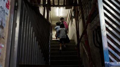 Ms Su is seen here walking up with her children to their rooftop hut. Anthony Wallace/AFP Photo