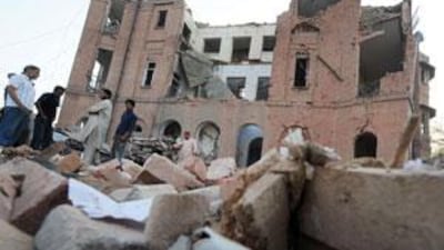 Pakistani residents stand in front of a destroyed police building a day after a suicide car bomb attack in Lahore.