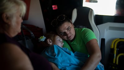 A Ukrainian woman holds her daughter in the back of an ambulance operated by Red Cross volunteers in Kupyansk, Kharkiv region. AP