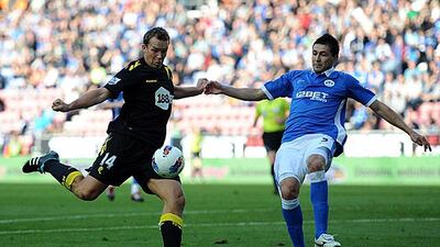 Kevin Davies, the Bolton striker, left, lines up a shot on goal as the Wigan defender, Antolin Alcarez, challenges. Chris Brunskill / Getty Images