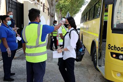 A staff member checks the temperature of a pupil outside Victoria English School in Sharjah. Pupils are back in the classroom at the emirate's private schools. Pawan Singh / The National