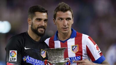 Atletico Madrid goalkeeper Angel Moya and forward Mario Mandzukic pose with the Supercopa de Espana trophy after winning it on Friday over Real Madrid. Dani Pozo / AFP