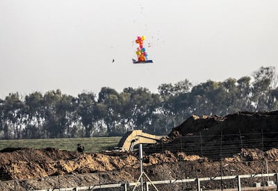 An Israeli soldier shoots at a balloon attached to a burning effigy sent over the border during Friday protests near the border between Israel and Gaza Strip. EPA
