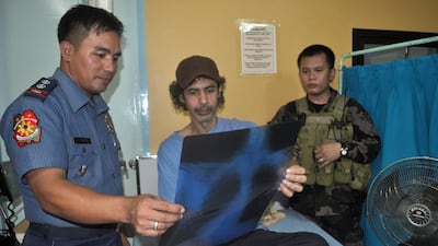 Jordanian TV journalist Bakr Atyani, centre, looks at the results of his medical check-up with Philippine policemen while resting at a hospital in Jolo after escaping Abu Sayyaf captors and ending an 18-month kidnap ordeal. AFP PHOTO