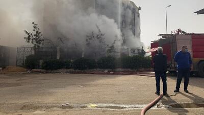 Men stand at the scene after a fire broke out in a garment factory north of Cairo, Egypt. Reuters