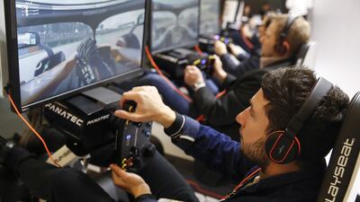 Attendees sit in race car seats and play a driving simulation game on the Formula One Management stand on day two of the MWC Barcelona. Bloomberg