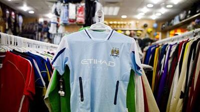 Imitation Manchester City shirts, like this one hanging in the Madinat Zayed shopping centre, will go on sale in Abu Dhabi today.