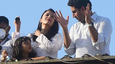 Bollywood actors Abhishek Bachchan and Aishwarya Rai Bachchan, along with their daughter Aaradhya, clap from atop a residential building to thank essential service providers during a one-day curfew imposed in Mumbai. AFP