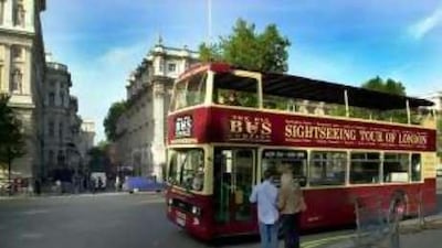 A double-decker sightseeing bus passes the gates of Downing Street in London.