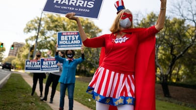 A person dressed in a 'Vote' superhero costume holds a campaign sign for Joe Biden outside a polling location in Atlanta, Georgia. Bloomberg