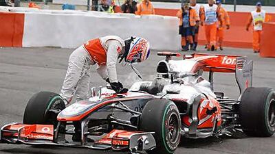 Jenson Button stands over his damaged McLaren-Mercedes after he was forced out of yesterday's Belgian Grand Prix following a collision with Sebastian Vettel's Red Bull-Renault.