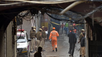 Indian police men stand in a lane as a National Disaster Response Force (NDRF) officer (C) walks the site where a fire broke out in New Delhi, India, 08 December 2019. According to news report, at least 40 people were killed after a fire broke out at a building in New Delhi's Anaj Mandi area. EPA