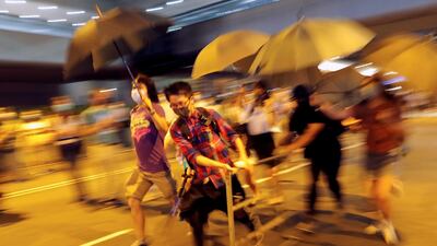 Anti-government protesters run carrying barriers as they block a street in Central Hong Kong, China. Reuters