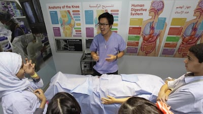 Dr Lewis Hou, a researcher at the University of Edinburgh, gives young visitors to the Abu Dhabi Science Festival the lowdown on emergency procedures before allowing them to ‘operate’ on a medical dummy ‘injured’ in a cycling accident. Jeffrey E Biteng / The National