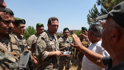 Lebanese army officers speak with villagers waiting to return to their homes at the entrance to Zawtar Al Gharbiyeh. Reuters