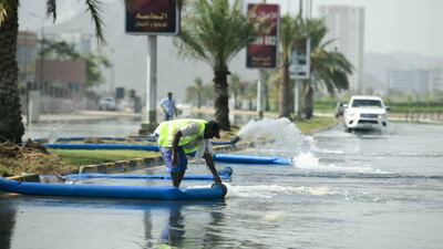 Municipality workers drain water from a flooded road in Fujairah. Khushnum Bhandari / The National