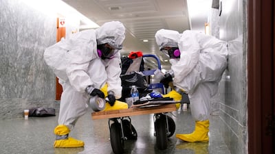 Workers seal their feet into hazmat suits as they prepare to clean the Senate Special Committee on Aging offices after a person reportedly tested positive for coronavirus. Reuters