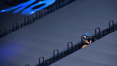 A photographer sits next to covered seating on day nine of the Australian Open tennis tournament in Melbourne. AFP