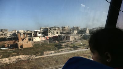 A convoy transporting Syrian civilians and rebel fighters drives past destroyed buildings in Arbin in Eastern Ghouta as they are evacuated from the opposition enclave to the village of Qalaat al-Madiq, some 45 kilometres northwest of the central city of Hama, on March 25, 2018. Abdulmonam Eassa / AFP