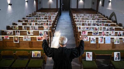 The evangelical pastor Klaus-Martin Pothmann stands in front of photos of believers who were asked to send in pictures to represent them among the pews at the St. Pankratius church in Hamm, western Germany. AFP