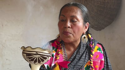 An indigenous woman makes a smoke offering in memory of her relatives. EPA