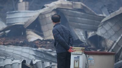 A resident looks at a gutted house after a massive fire engulfed the area in Sokcho, South Korea. EPA