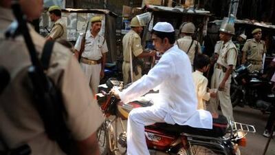 Indian paramilitary troops stand guard as an Indian Muslim rides past near a mosque in Ayodhya last week. A reader advises Indians to set aside old squabbles over temples and concentrate on modernising their country.