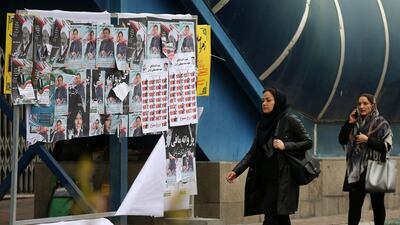 Iranian women walk past electoral posters. AFP