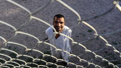 A male patient looks through a fence as he stands outside in the yard.